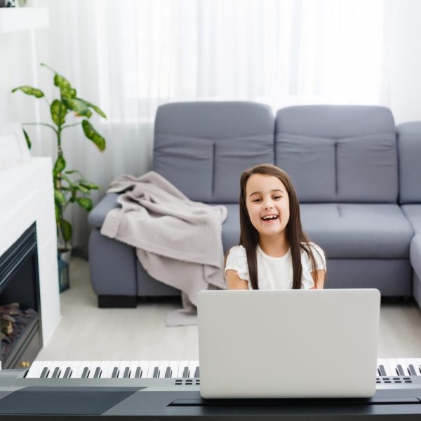 Un piano numérique compact installé dans un petit salon, près d’un canapé et d’une fenêtre.