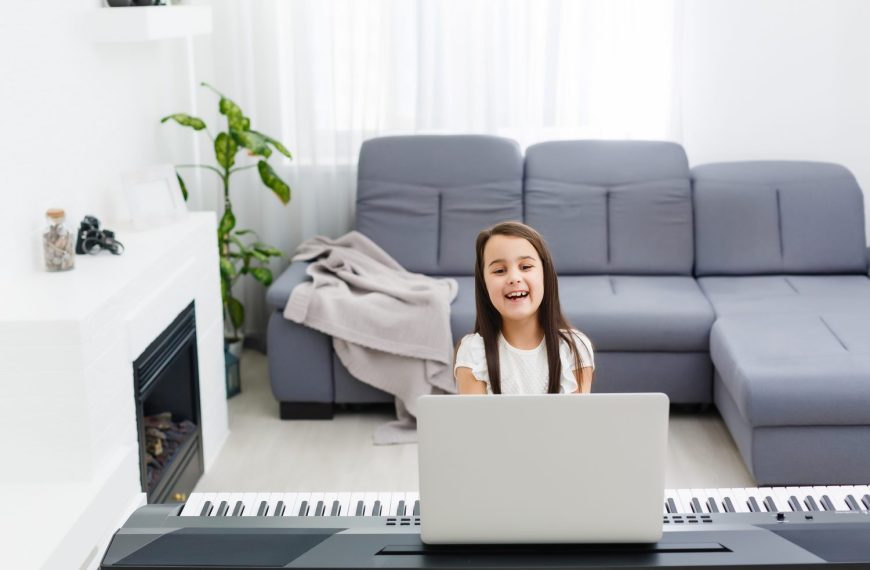 Un piano numérique compact installé dans un petit salon, près d’un canapé et d’une fenêtre.