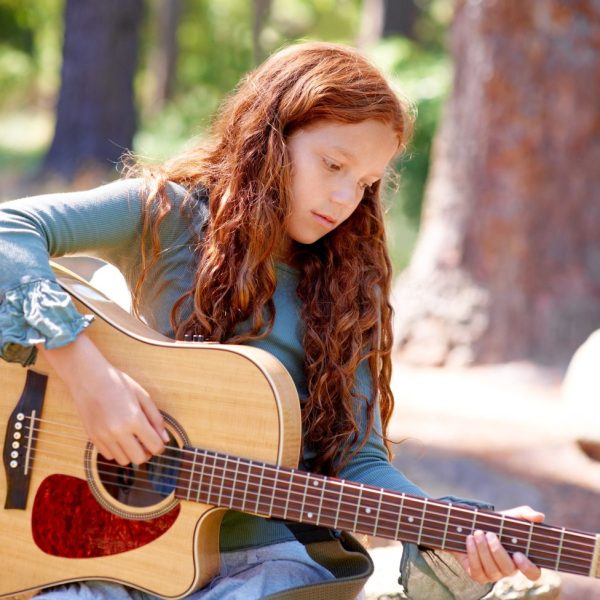 Enfant de 7 ans jouant de la guitare adaptée à sa taille.