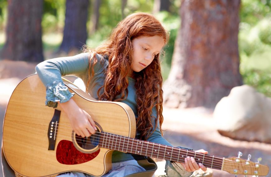 Enfant de 7 ans jouant de la guitare adaptée à sa taille.