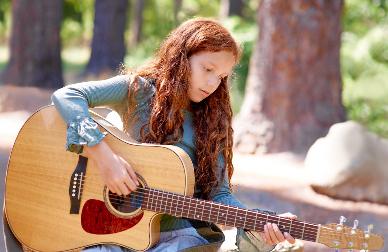 Enfant de 7 ans jouant de la guitare adaptée à sa taille.